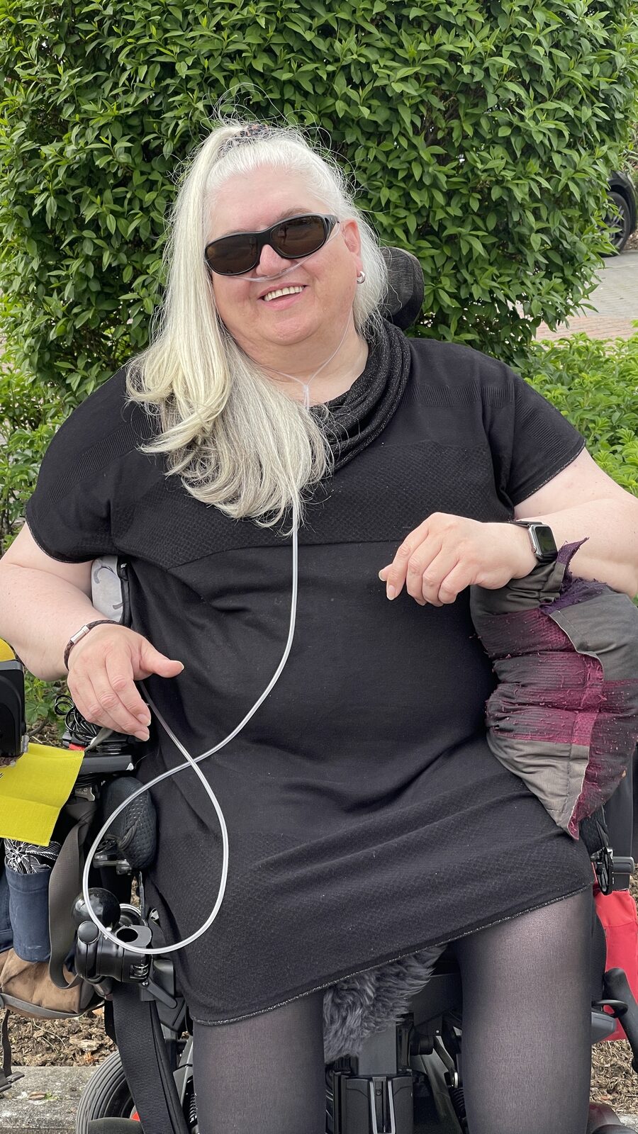Susanne Steffgen im Rollstuhl vor einer grünen Hecke